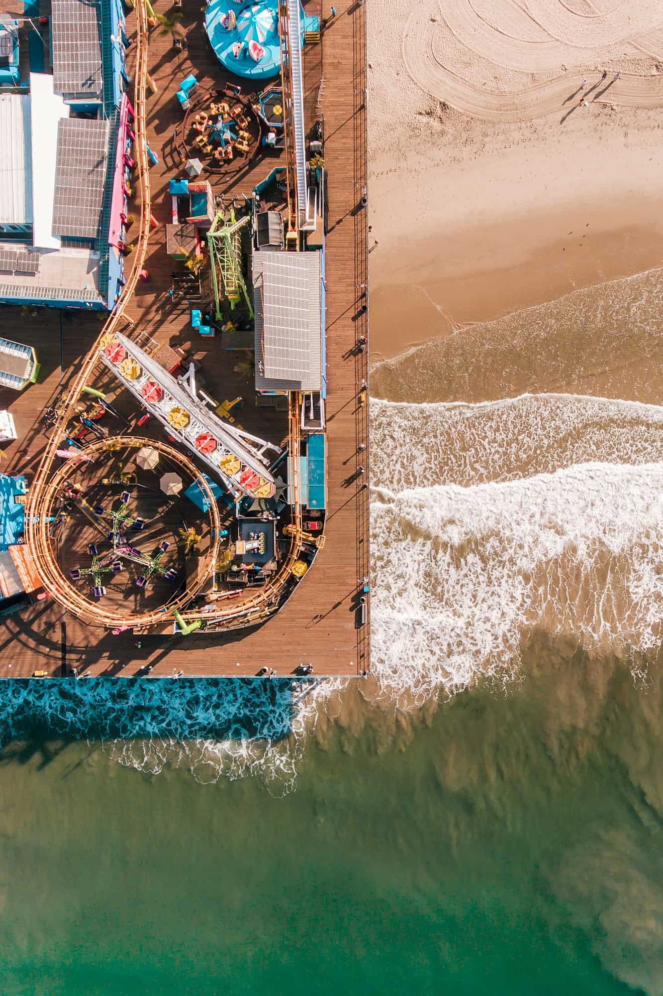 the santa monica pier next to the ocean and beach seen from above